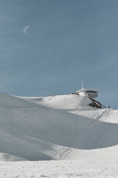 A snowy mountain slope with an observatory under a clear sky in Andorra.