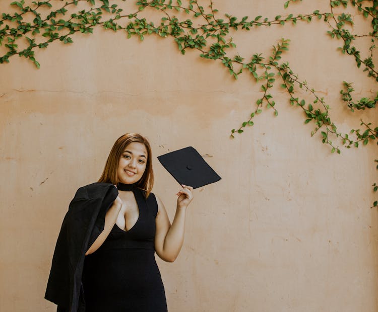 Cheerful Woman With Graduation Cap In Hand