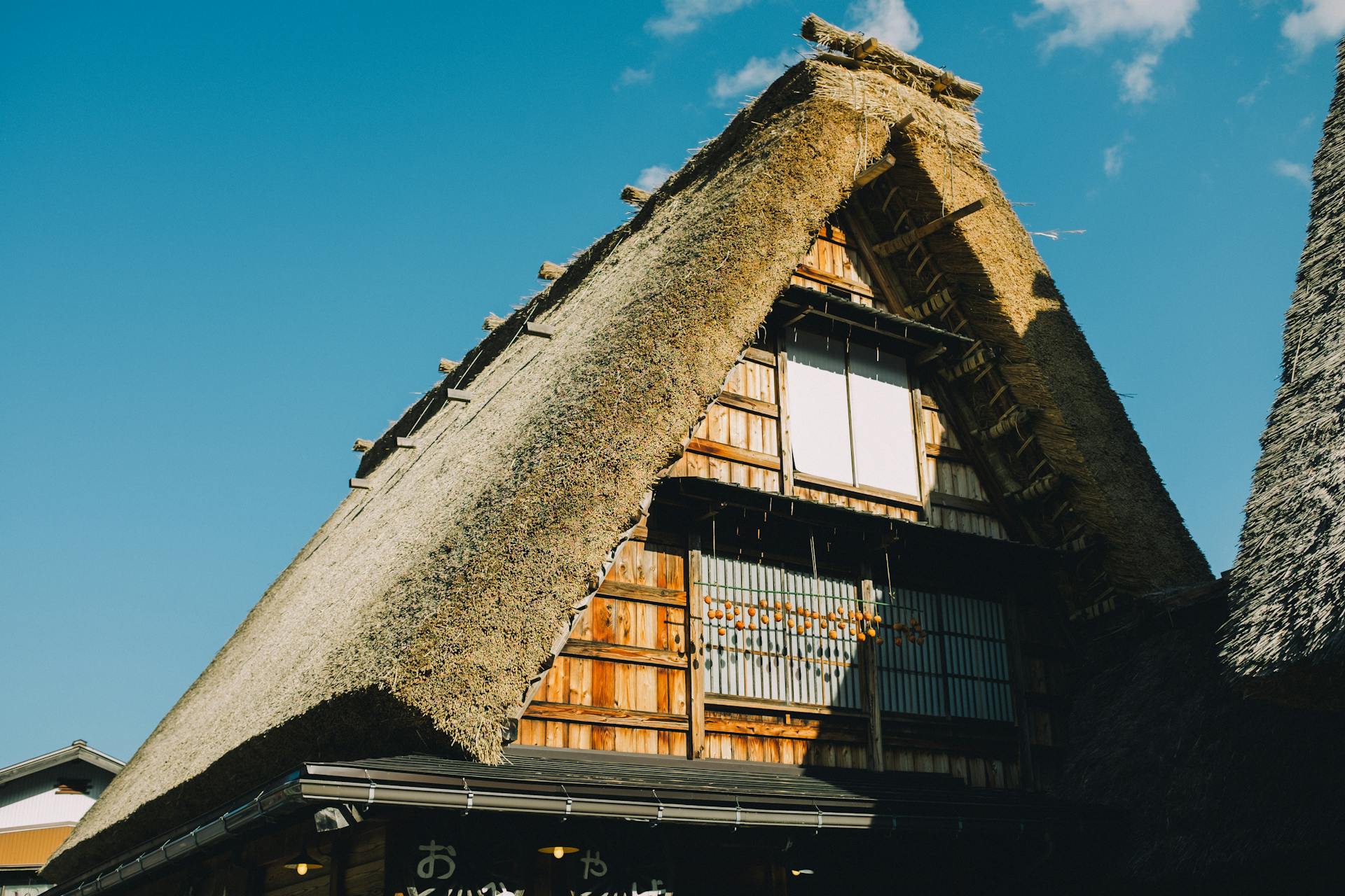 Gorgeous shot of a traditional Japanese thatched roof house under a clear blue sky.