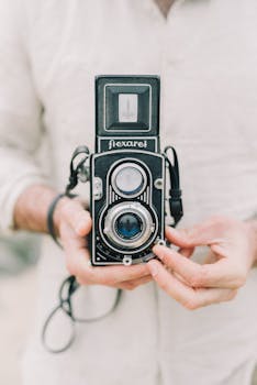 Close-up of hands holding a classic vintage film camera, showcasing retro design.