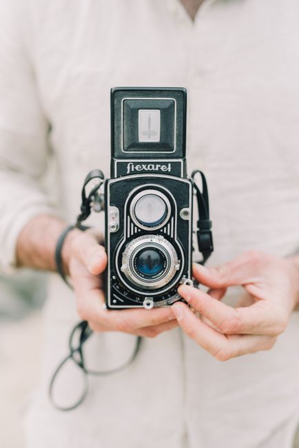 Close-up of hands holding a classic vintage film camera, showcasing retro design.