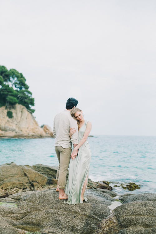 Uomo E Donna Che Baciano Sulla Roccia Marrone Vicino Al Mare