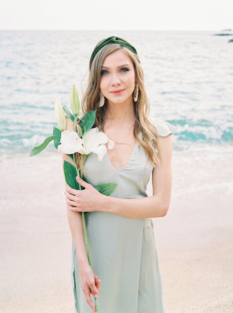 Woman Standing On Beach Holding White Flower