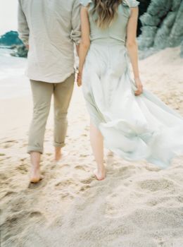 一对夫妇手牵着手在沙滩上漫步，显得浪漫而团结