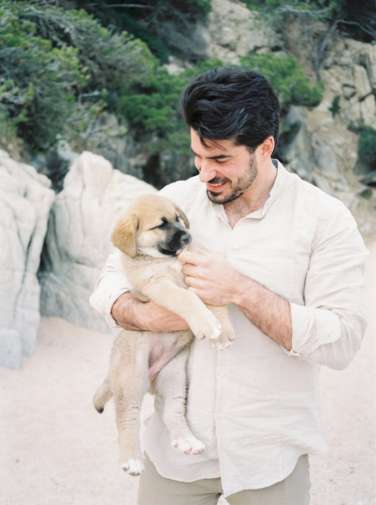 Smiling Man Carrying A Puppy