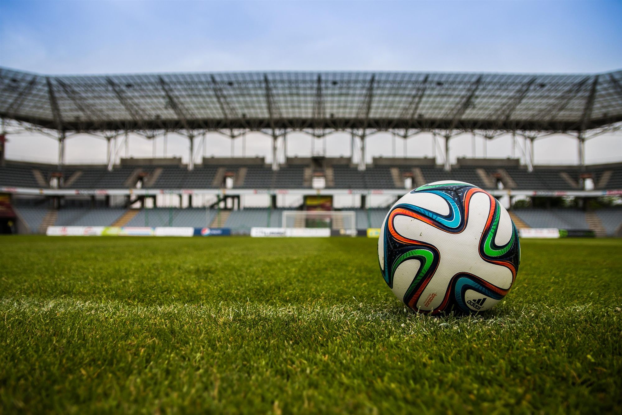 Balón de futbol sobre el césped de un estadio vacío