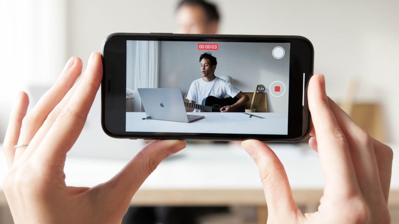 Musician recording promotional content for a new single with a smartphone