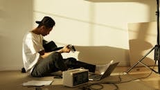 Man in White Dress Shirt and Black Pants Sitting on Chair Using Macbook Pro