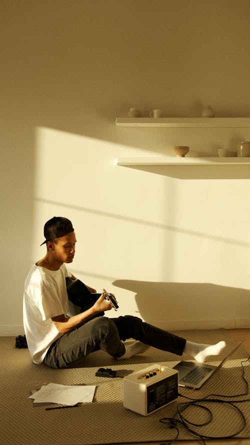 Man Sitting on the Floor Playing a Guitar