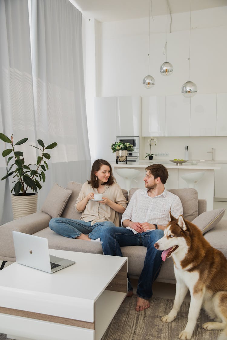 Couple Relaxing On A Sofa With Their Husky Dog