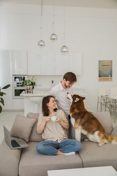 在现代客厅的沙发上，一对快乐的夫妇正带着他们的狗放松身心
