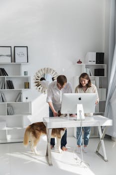 Bright home office with two adults and a dog, featuring Scandinavian design and minimalist decor.