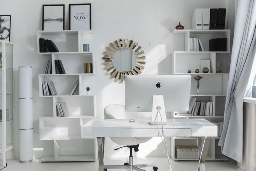 Bright minimalist home office setup with white shelves, desk, and iMac. Ideal for productivity.