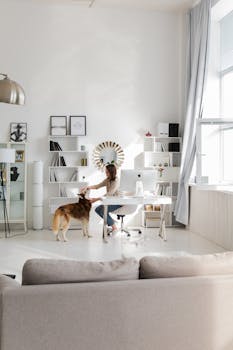 Bright home office featuring a woman petting her dog at the desk. Ideal for remote work themes.