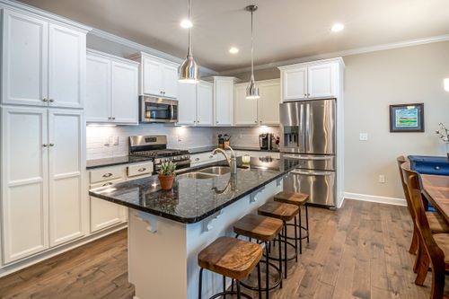Free Elegant modern kitchen featuring white cabinets and a black marble island. Stock Photo