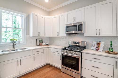 White Wooden Kitchen Cabinet and Black Microwave Oven