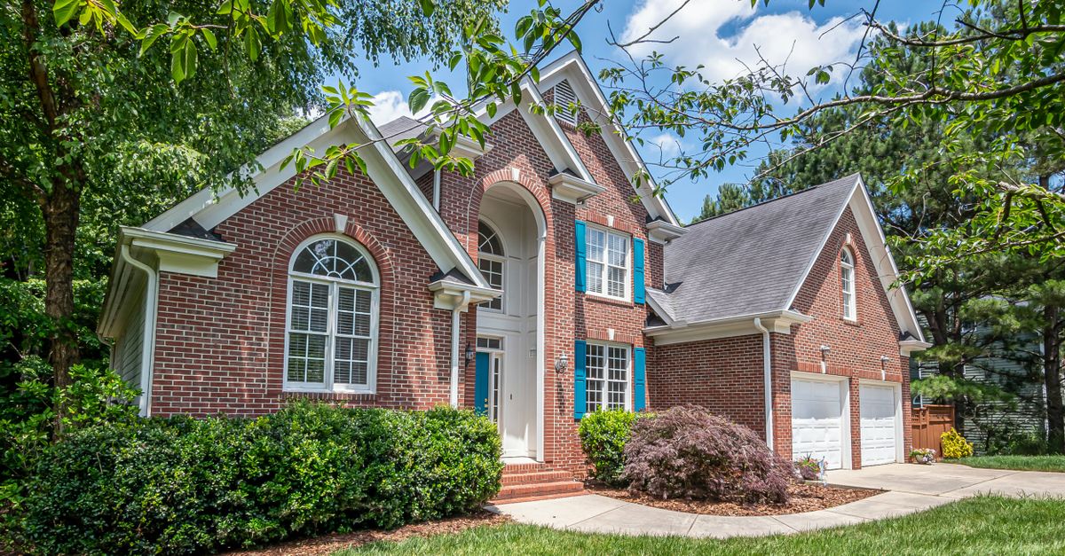 Beautiful brick suburban house surrounded by lush greenery, showcasing classic architecture.