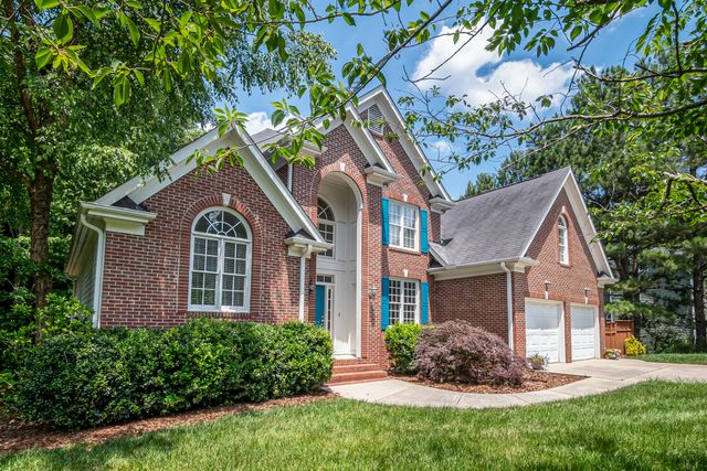 A brick suburban home framed by mature greenery. Photo by Curtis Adams on Pexels.