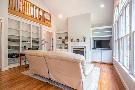 Bright and spacious living room featuring a luxurious couch, high ceilings, and a cozy fireplace.