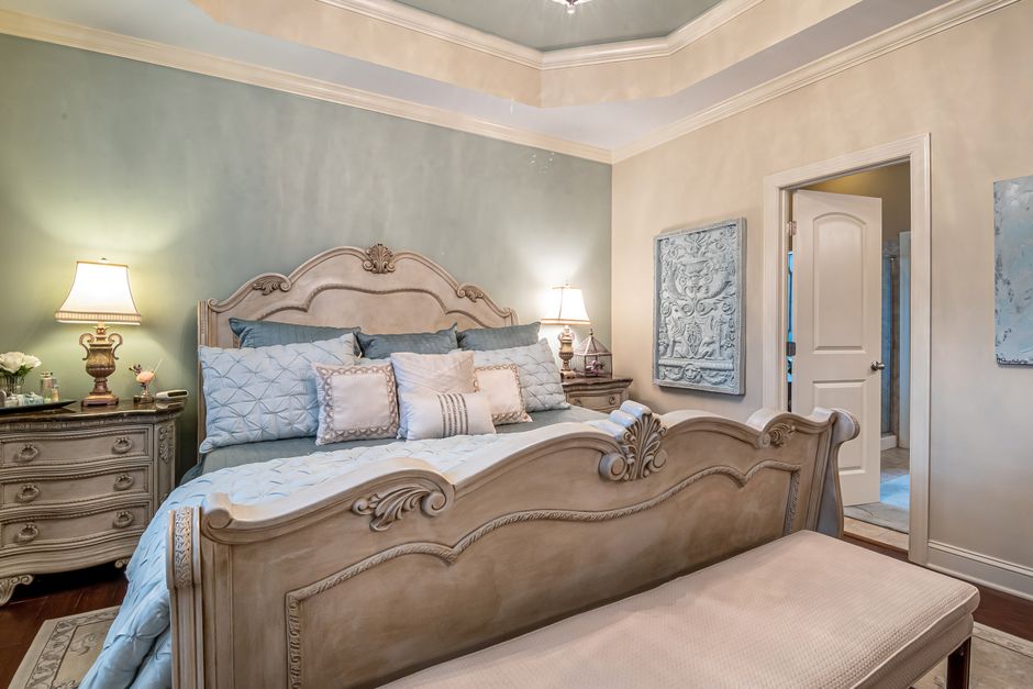 A styled bedroom featuring lion-colored linen sheets, sage green pillows, and light wood nightstands