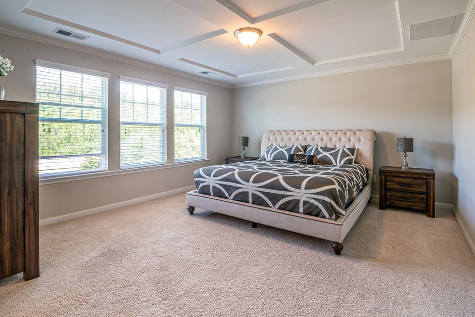 Spacious modern bedroom with a plush bed, large windows, and elegant decor, perfect for an airy feel.