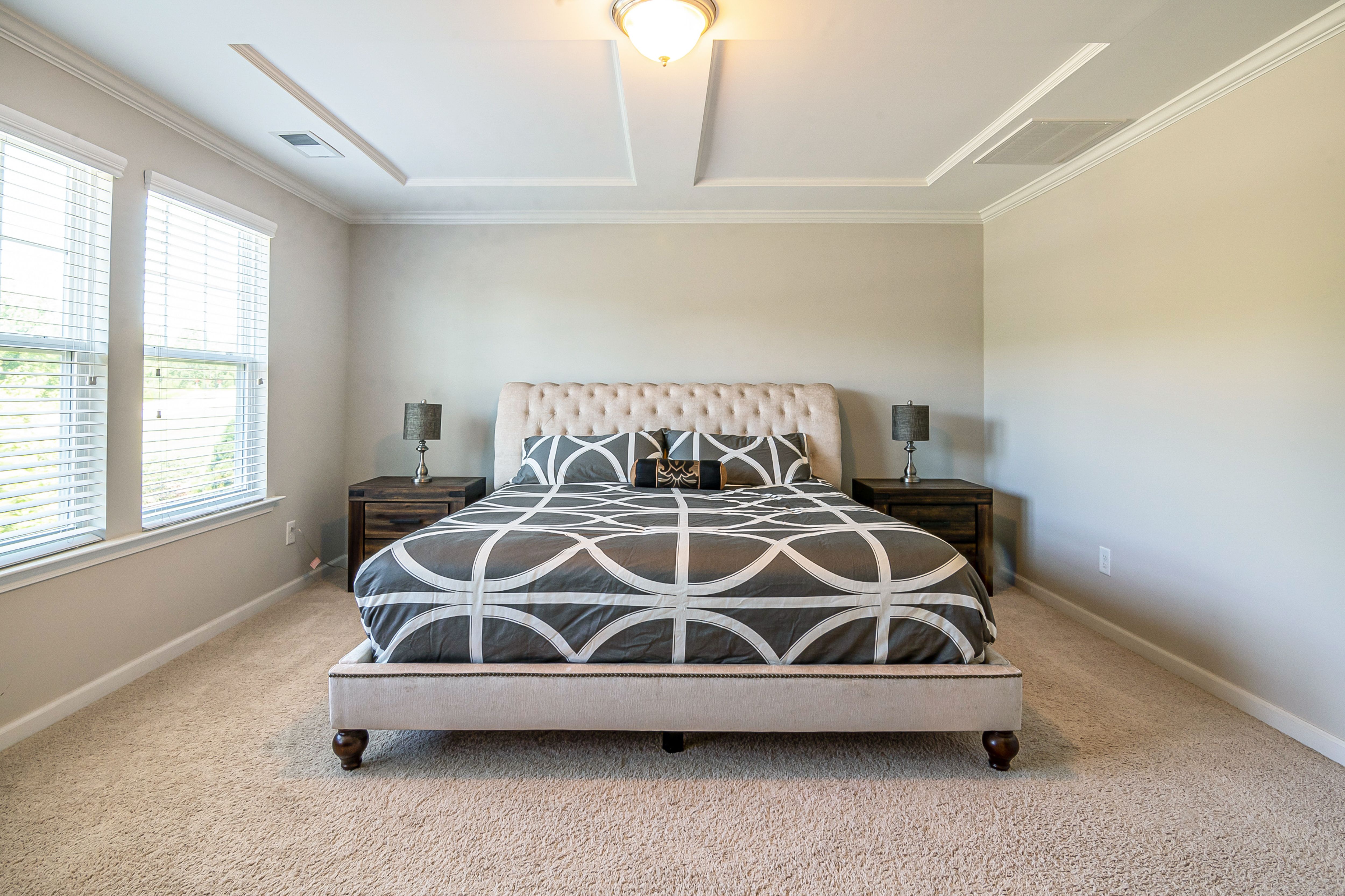 Spacious modern bedroom featuring a stylish bed and ample natural light.