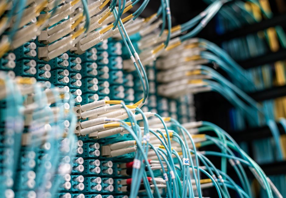 From below of long thin blue cables connected to row of small white connectors on system block in data center