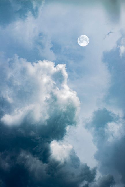 A captivating view of clouds and full moon in a serene blue sky, perfect for nature themes.