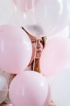 在庆祝节日、点缀着闪光妆容的柔和桃红色气球中，一位少妇静立其间