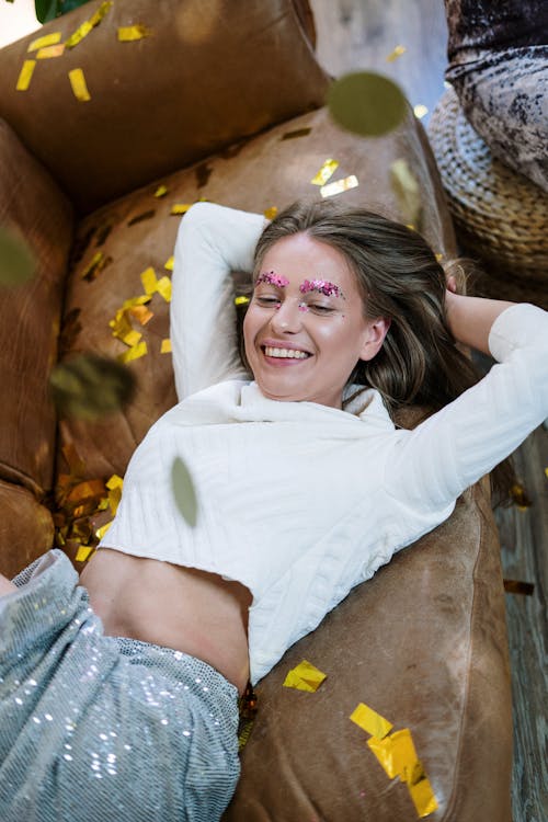 Smiling Woman in White Long Sleeve Shirt and Blue Denim Shorts Sitting on Brown Wooden Log