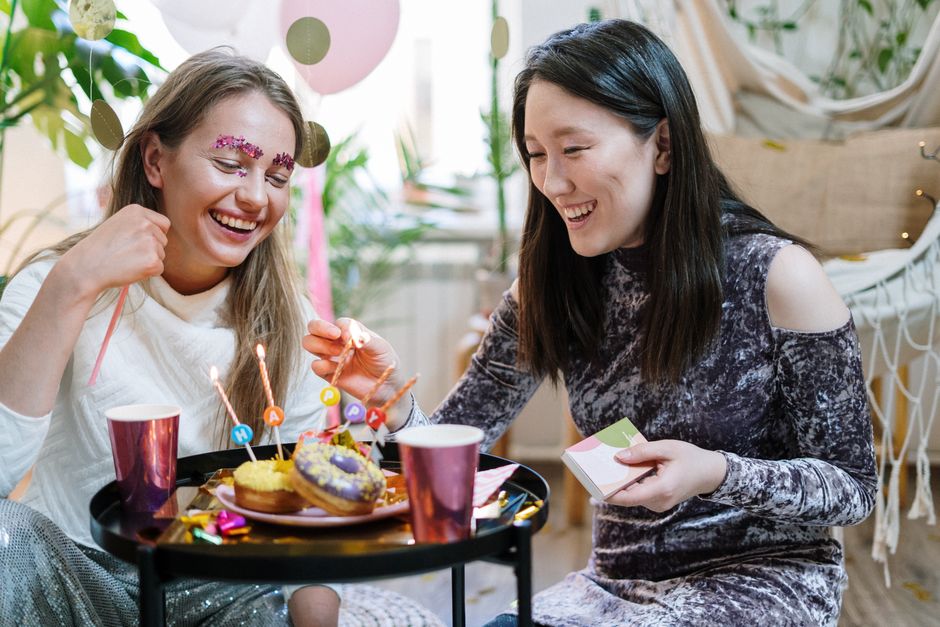 engraved gift ideas for best friends - Two women celebrating a birthday indoors with sweets and laughter.