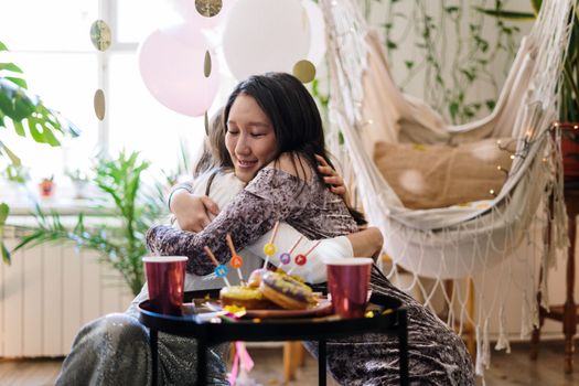 在喜庆的室内生日庆祝活动中，两个朋友用气球和糖果拥抱在一起