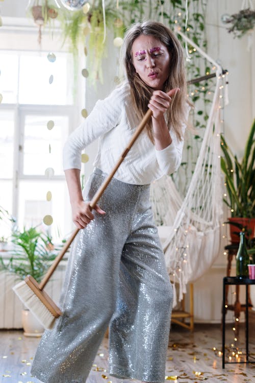 Woman in White Long Sleeve Shirt Holding Brown Wooden Stick