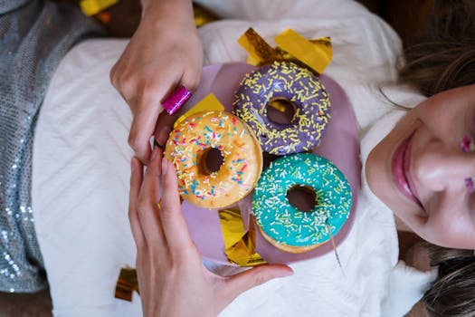 在节日的室内庆祝活动中，一位面带微笑的女子手持着撒满糖霜、色彩鲜艳的甜甜圈