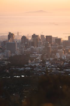 A breathtaking aerial view of a city skyline enveloped in morning mist during sunrise.