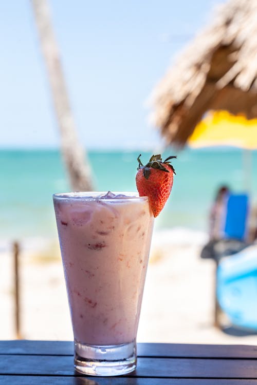 Glass of milkshake with strawberry on table