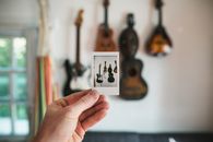 Crop person showing photo of assorted musical instruments at home