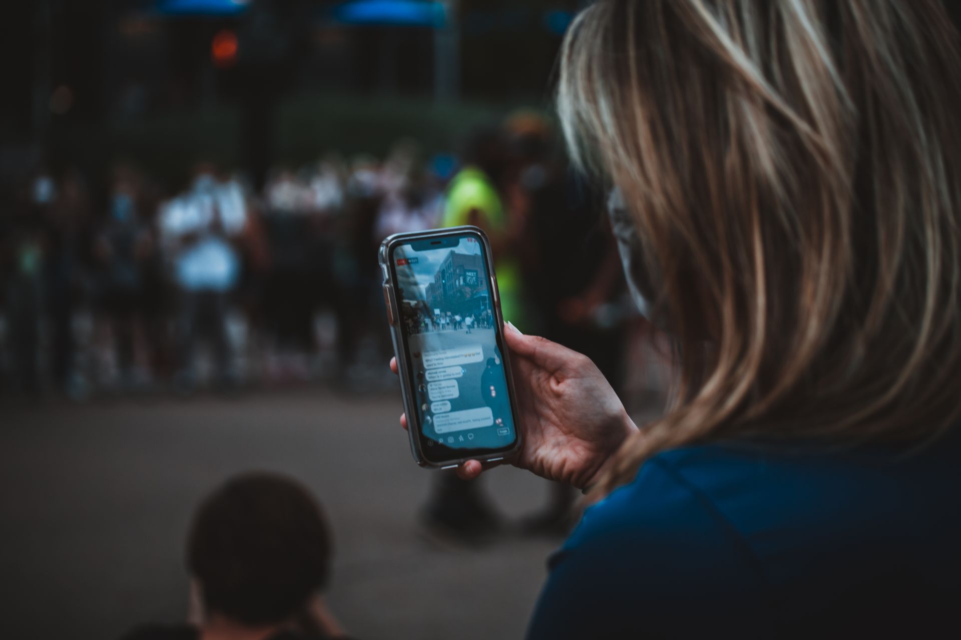 A woman using a smartphone during a protest on a city street.