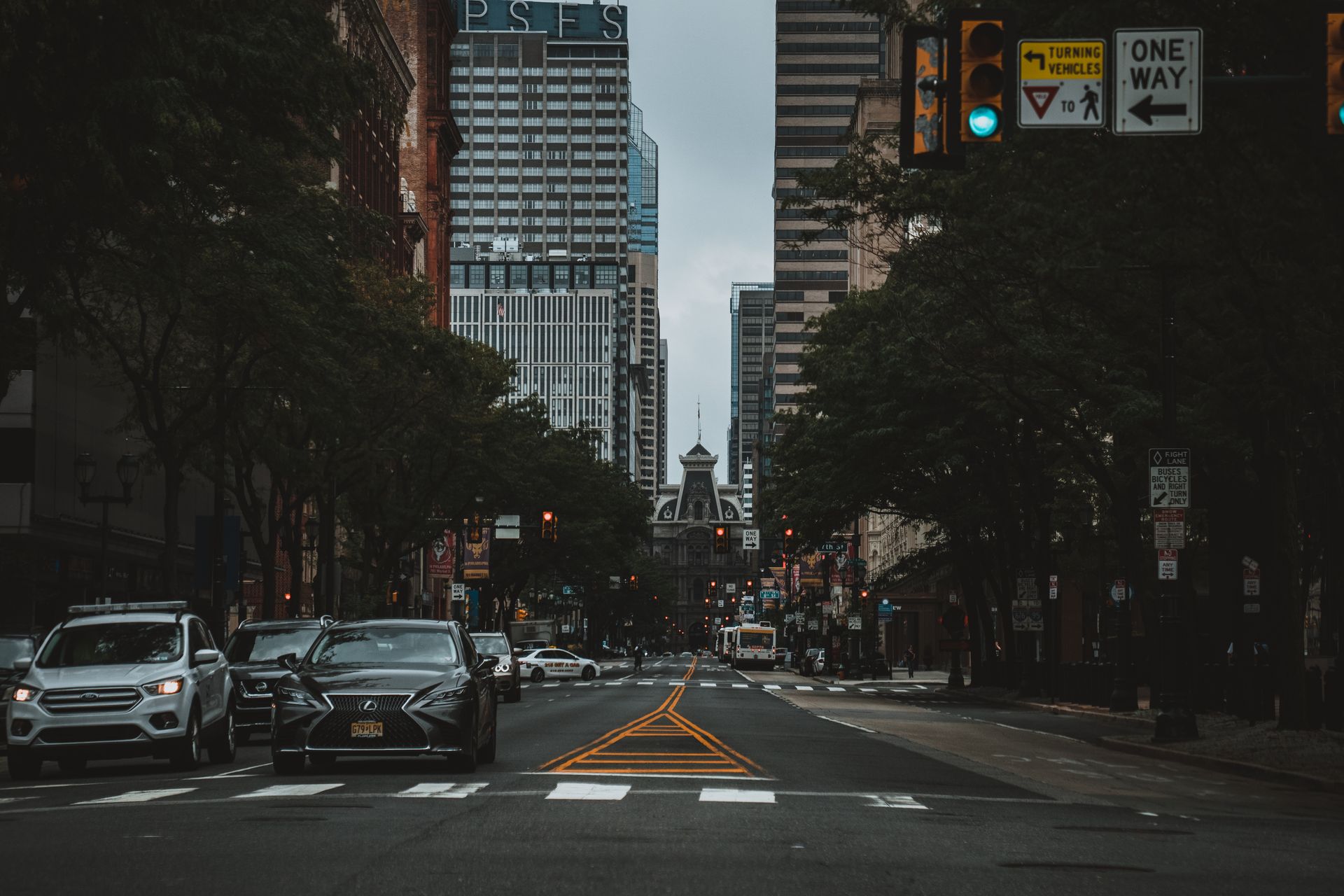 City street view with cars, skyscrapers, and visible PSFS building in downtown area.