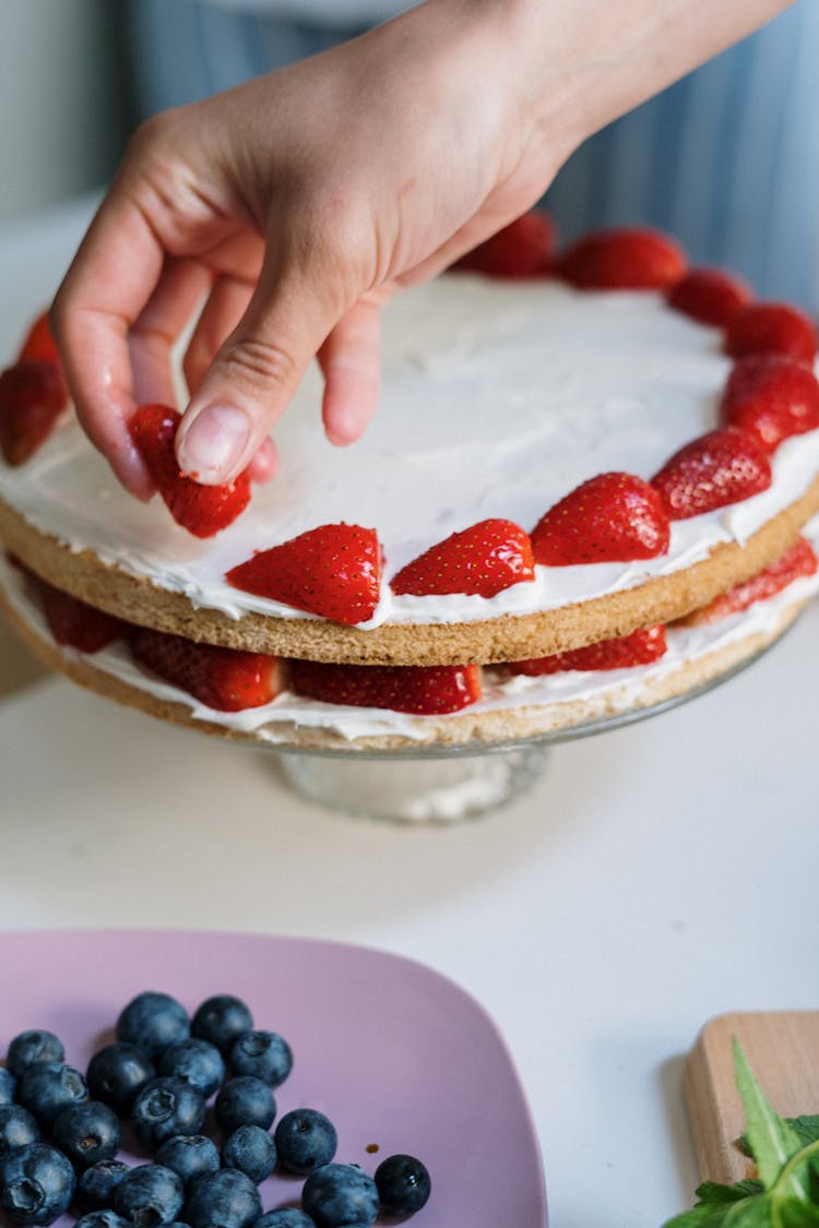 Person Holding Strawberry Cake On White Ceramic Plate