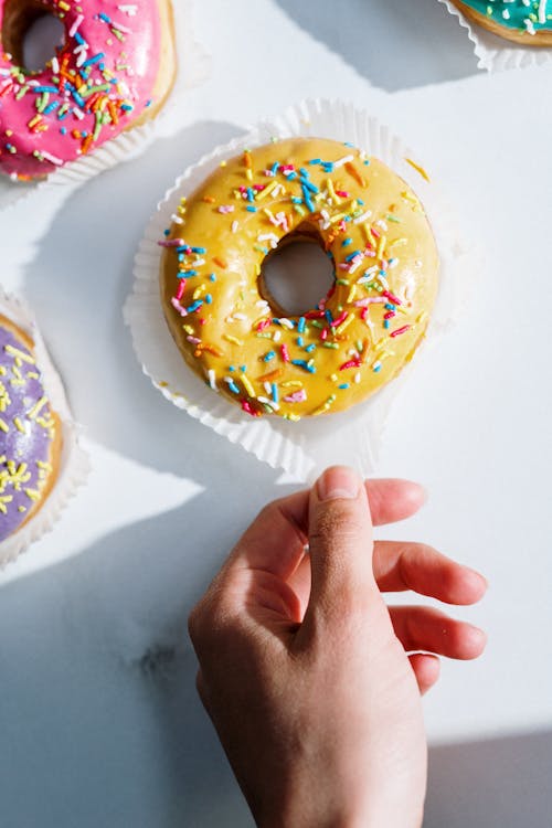 Person Holding Doughnut on White Paper