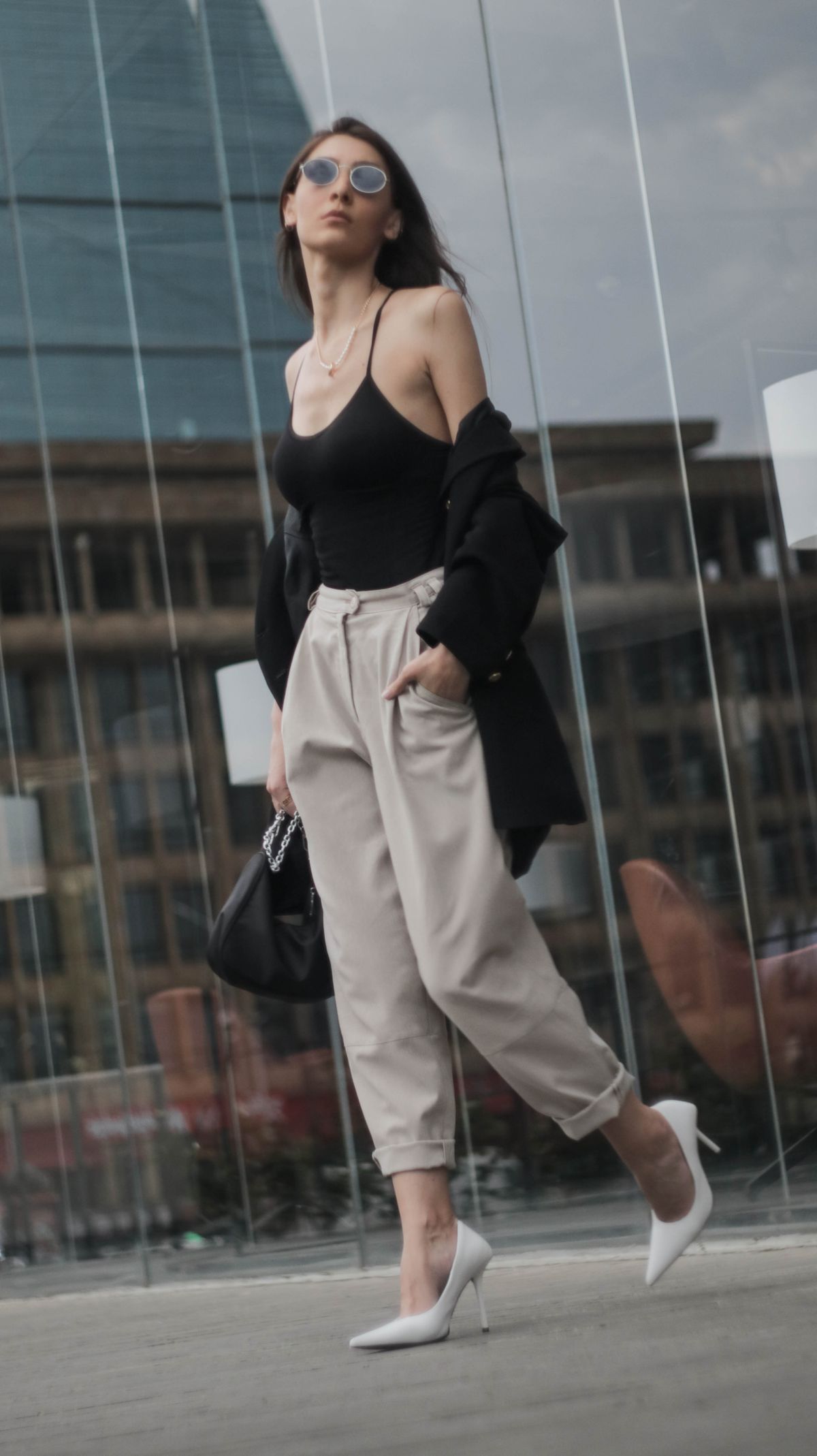 A fashionable woman walking near a glass wall — the editorial capri-pant outfit