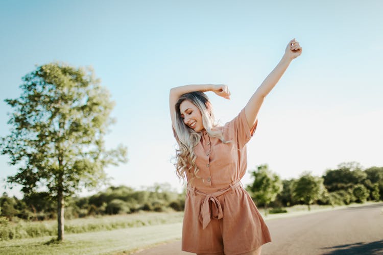 Photo Of Carefree And Smiling Woman In Brown Button Front Belted Romper 