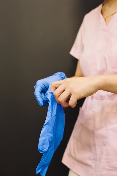 A Person in Pink Scrub Suit Wearing Medical Gloves