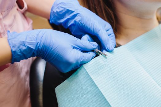 Dentist with medical gloves adjusting a dental bib on a patient in close-up view.