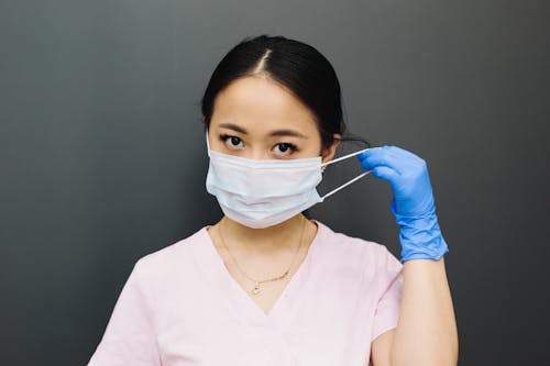 Woman in Pink Scrub Top Putting On A Face Mask