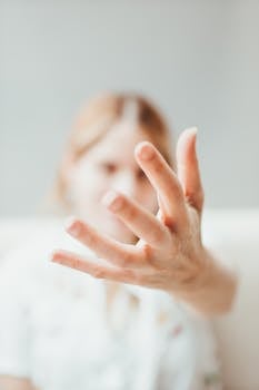 Blurry portrait of a woman reaching out with focus on hand. Artistic style.