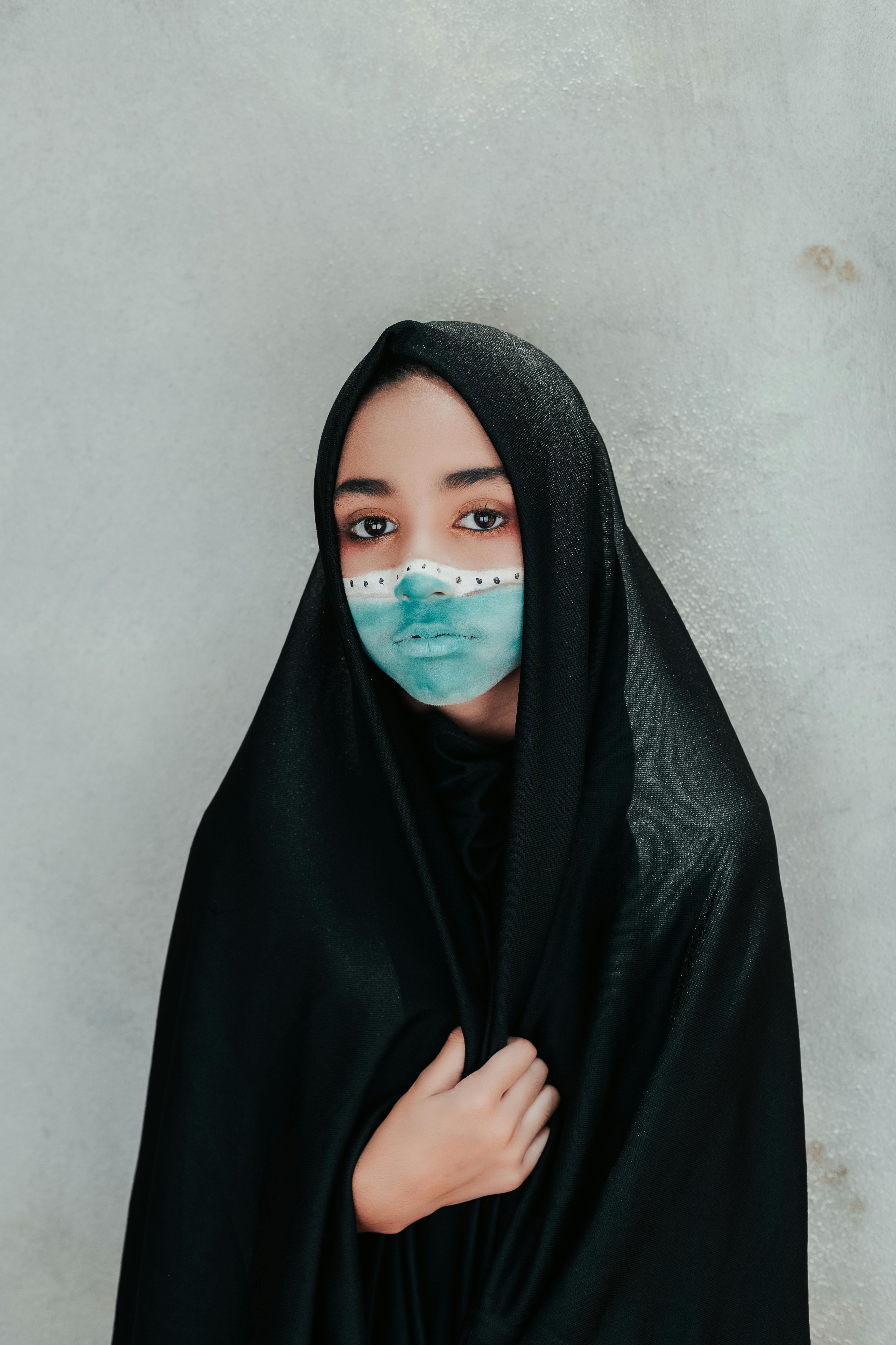 Young woman in black veil with artistic face paint, showcasing cultural fashion and expression.