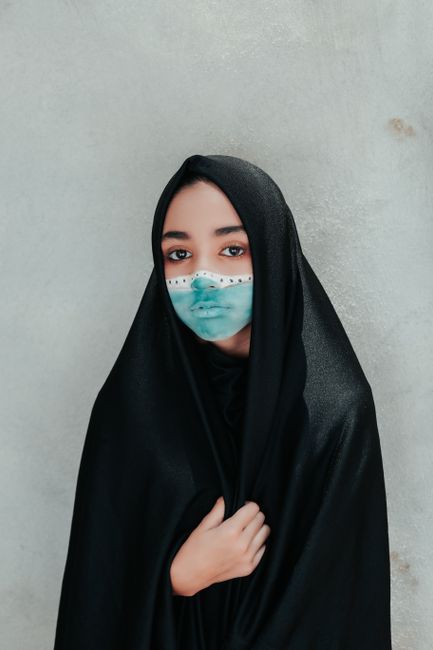 Young woman in black veil with artistic face paint, showcasing cultural fashion and expression.