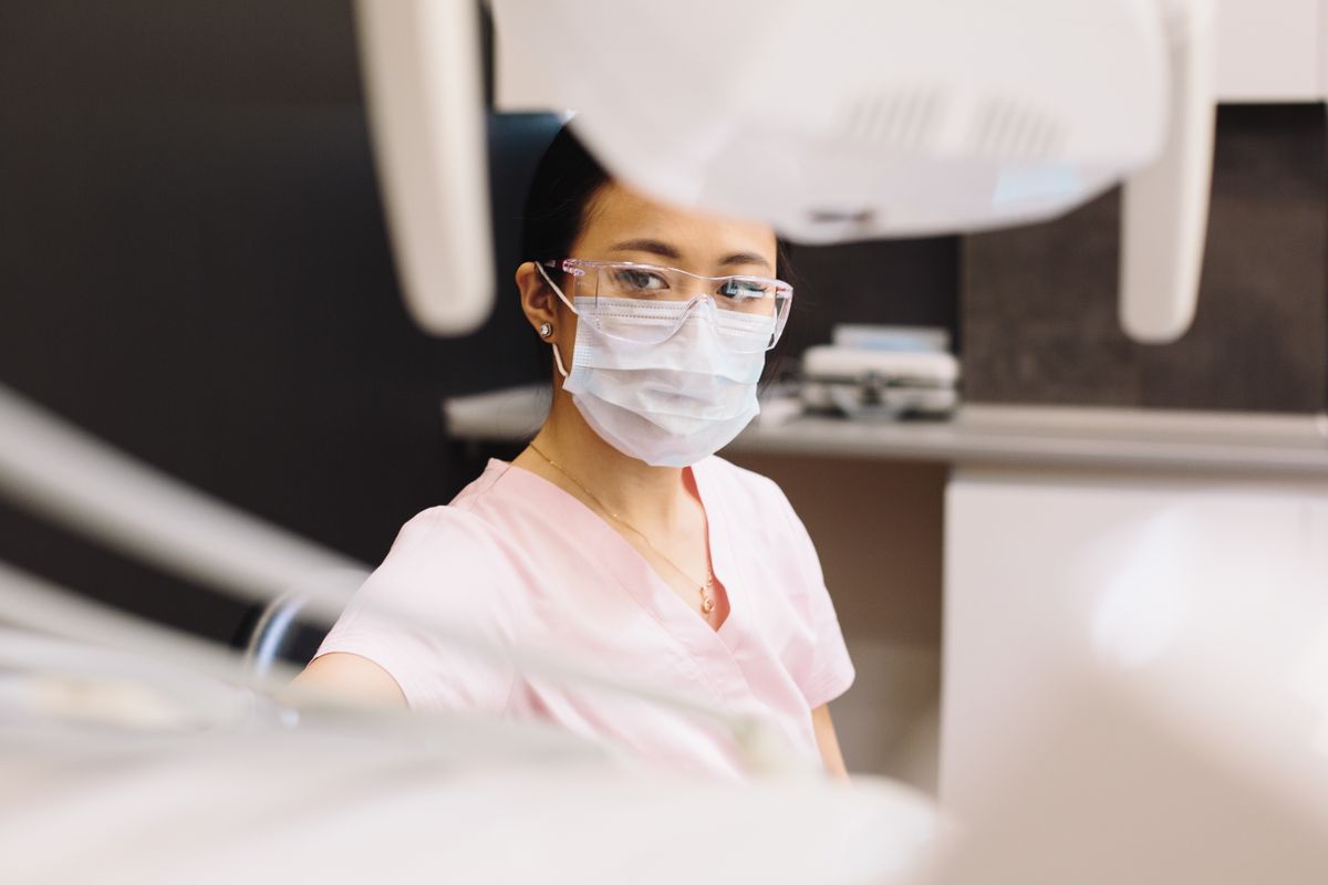 Asian female dentist wearing mask and glasses in a modern dental clinic